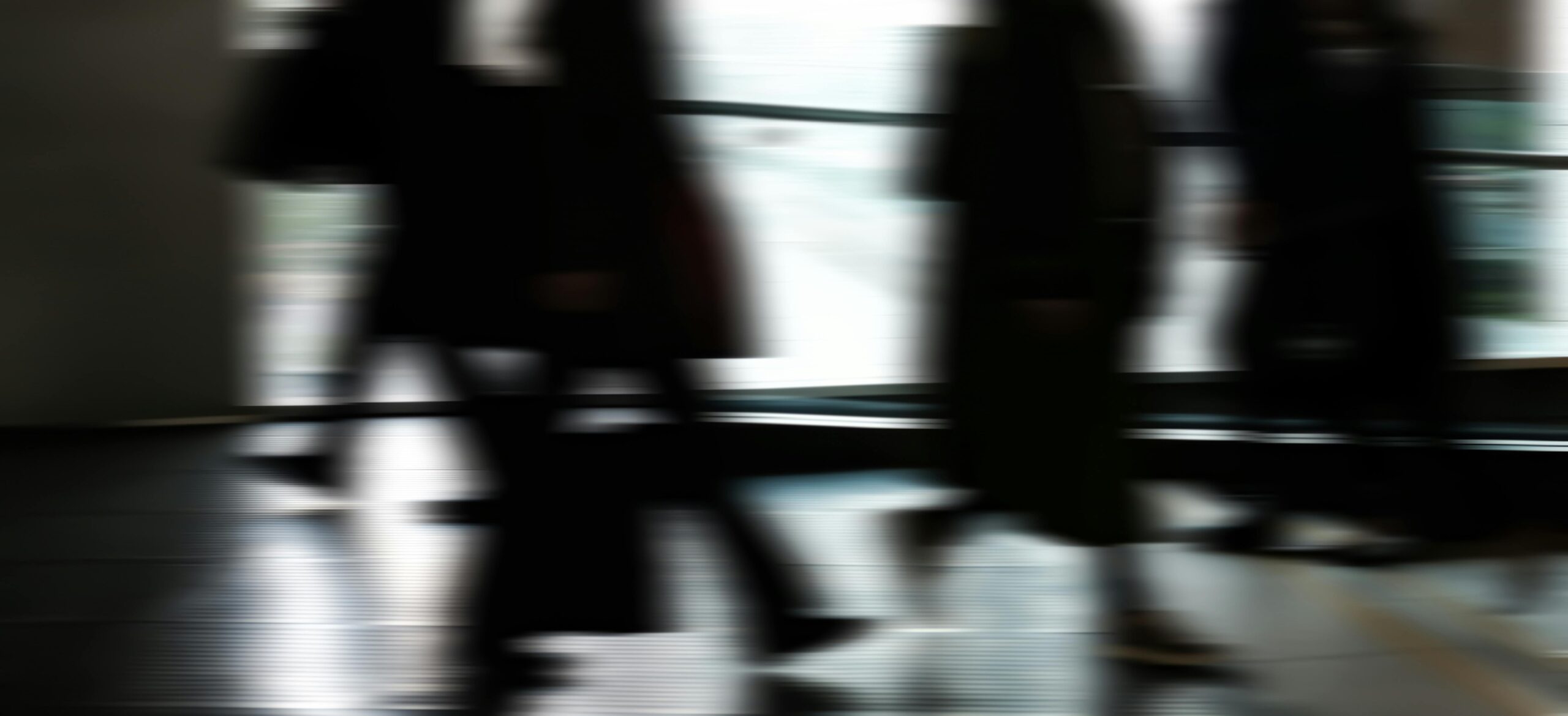Abstract blurred motion of people walking indoors, depicting urban life and busy routines.